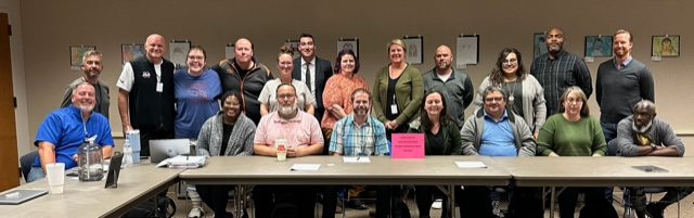 Group of Putnam City Teachers, and participants in SNU's MAEL program, sitting at a table and standing around it.